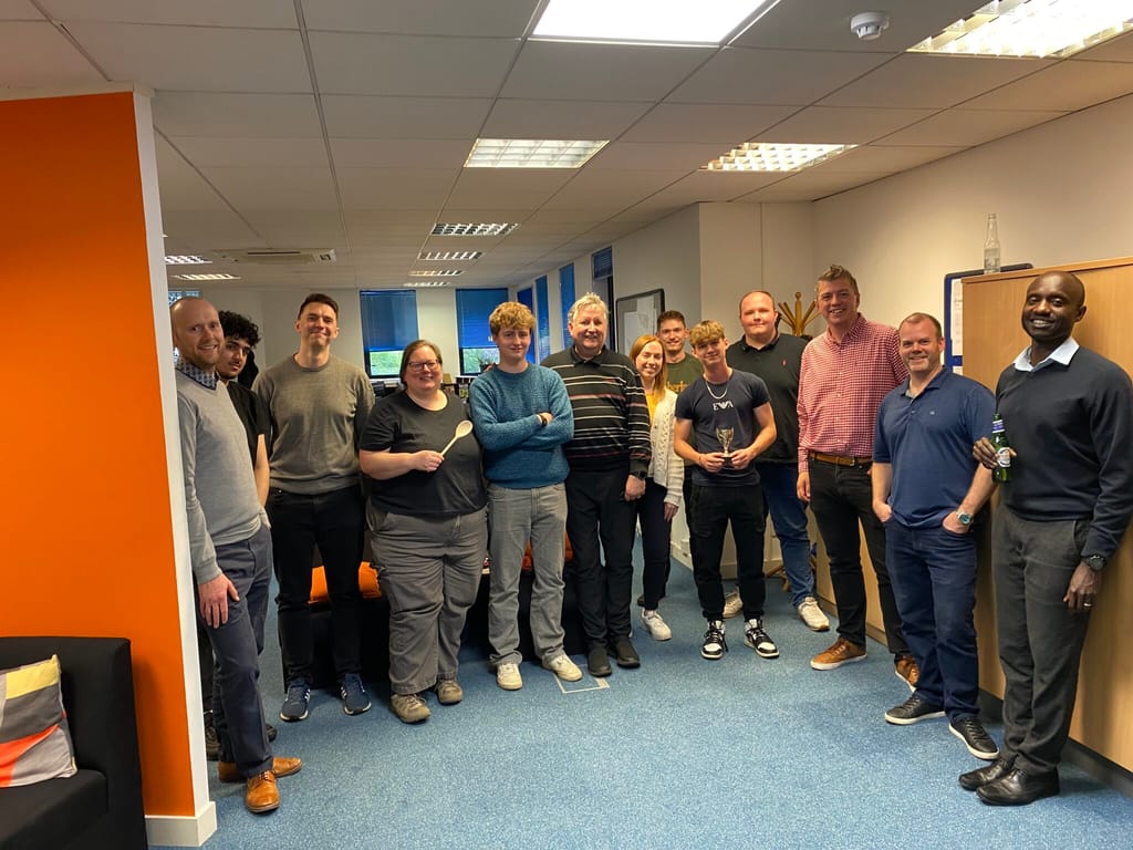 The team gathered in the office after the cornhole tournament